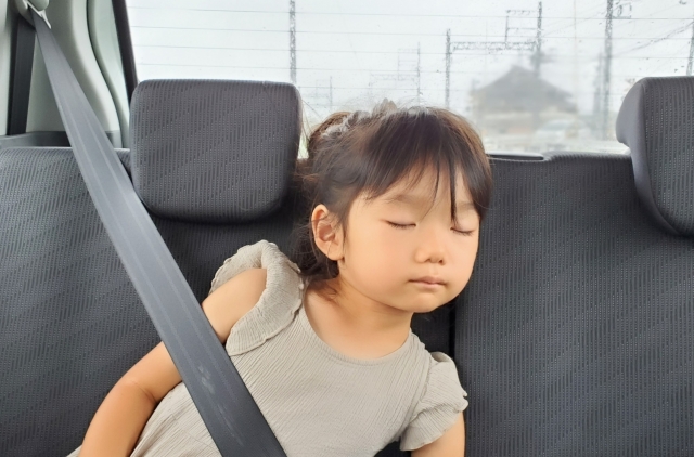 子どもが車中で寝ているイメージ